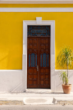 Traditional Yucatan architectural elements in Mexico - bright yellow wall, blue doors, and potted plants.