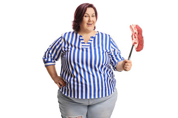 Corpulent woman holding a raw steak with a big fork