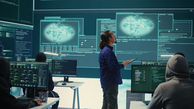 Group of professional hackers gaining access into government database to steal important information for hybrid warfare. Experts work on scams and phishing activity in high tech office. Camera B.