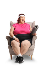 Lazy plus size woman sitting in an armchair and holding an exercise mat