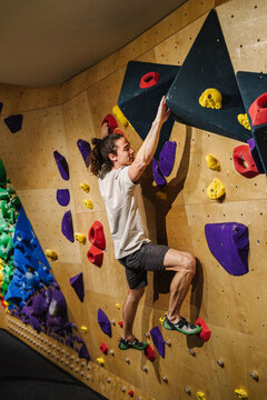 Man climbing indoor wall with large black triangle holds