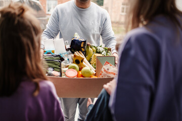 Family receiving box of groceries from courier