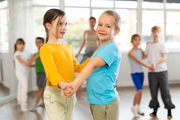 Group of schoolchildren training movements of slow foxtrot in dance studio with female tutor