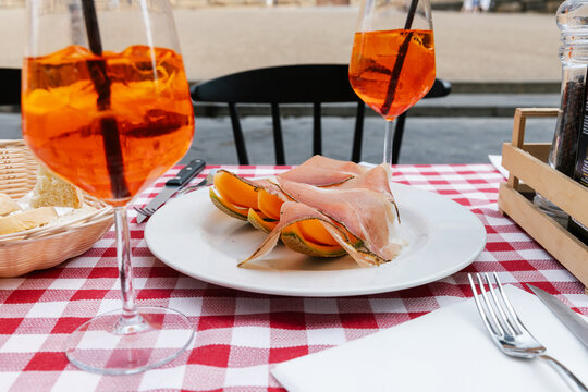 Two aperol spritz's with prosciutto and cantaloupe slices