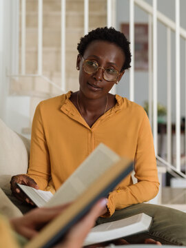 Young black woman reading book and listening to her roommate