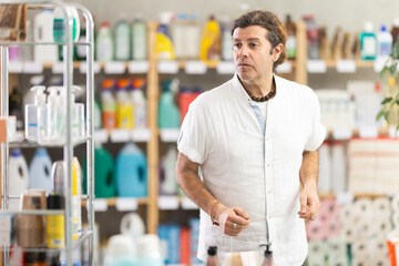 While shopping, man walks through household store, studies windows, looks at assortment of goods,...