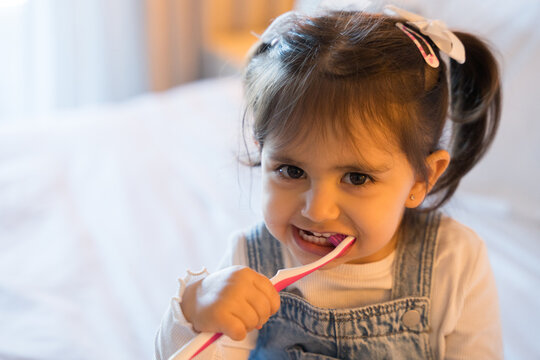 Cute little girl brushing teeth in hotel room during family vacation