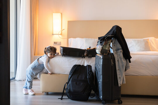 Little girl playing near suitcases and backpacks in hotel room