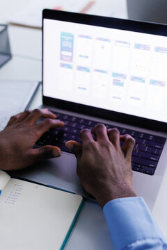 Anonymous office employee typing something on laptop sitting at desk