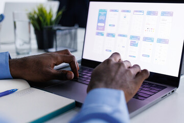Anonymous data expert analyzing charts on laptop sitting in office