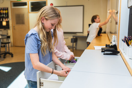 Girls Organizing Supplies in Classroom