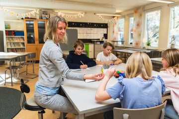 Teacher Assisting Students with Project in Classroom