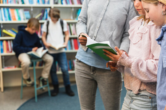 Teacher Reading with Students in a Library at school