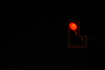 vibrant red traffic light glowing brightly against a pitch-black night sky, symbolizing stop, caution, and urban nighttime ambiance