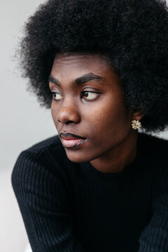 Woman with natural afro hairstyle in black sweater poses indoors
