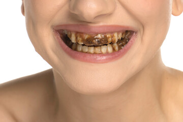 Close-up of young woman with chocolate-stained teeth smiling after bite, studio shot on white background