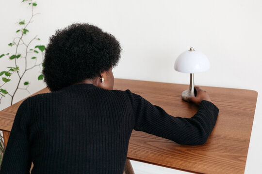 Person adjusting a sleek desk lamp in a modern interior setting