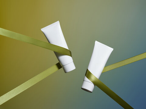 Stylish white cosmetic tubes elegantly wrapped in green ribbons