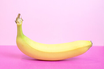 Fresh yellow banana isolated on vibrant pink background, healthy tropical fruit with pop art aesthetic, concept of nutrition, fun food styling and vegan lifestyle