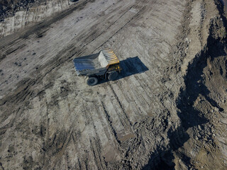 Heavy quarry dump trucks carry coal in their backs.