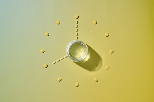 Pills arranged in a clock formation with water cup