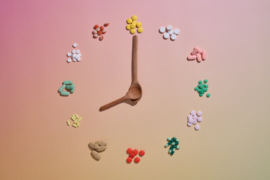 Pills arranged like clock numbers with a spoon marking the time