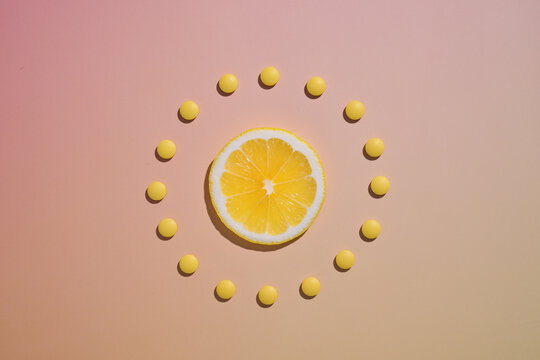 A lemon slice surrounded by yellow pills in a circle