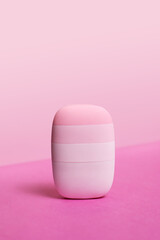 Minimalist pink silicone facial cleansing device on vibrant pastel background, modern skincare and beauty technology tool for gentle hygiene and self-care routine