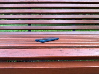 Smartphone left on a wooden park bench. Concept of lost device, forgotten belongings, or...