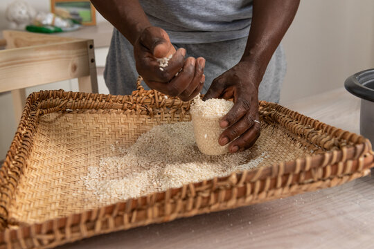 Black male hands putting rice into a cup after winnowing rice 