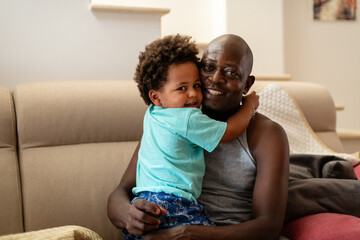 Happy father holding and hugging his toddler son at home