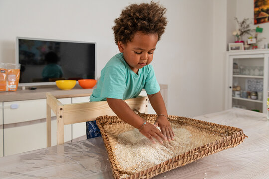 Curious african child playing with rice in a tipical congolese basket