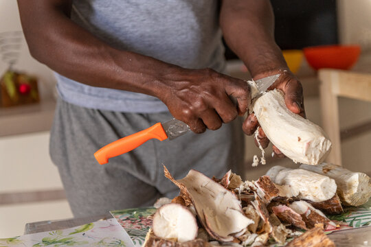 Black male hands peeling the cassava root in the kitchen