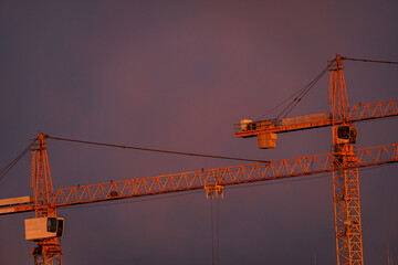 Two Tower Cranes Against Dramatic Sunset Sky