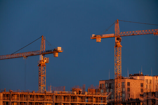 Tower Cranes at Sunset Over Construction Site