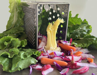 Vegetable display shows grater colander used in the kitchen with fresh produce. Lettuce, cabbage, ...