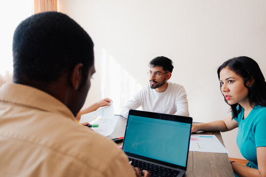 Three business people working together on a laptop in an office.