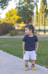 Fototapeta premium Curious toddler exploring a sunny park surrounded by greenery and vibrant colors