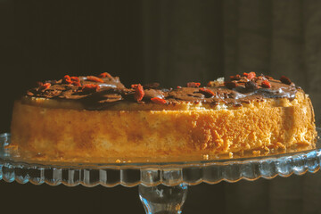 Traditional Polish bundt-style cake with rich chocolate glaze and goji berries, served on elegant glass stand, festive homemade dessert for Easter or special occasions