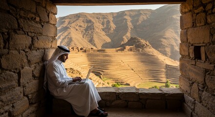 Remote Worker in Traditional Attire Enjoys Scenic Mountain View While Using Laptop