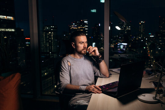 oung man working late on laptop with Warsaw cityscape