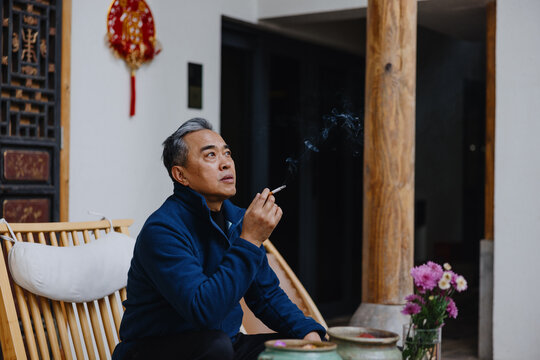 Man sitting and smoking cigarette indoors