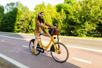 Overjoyed woman riding electric bicycle with her legs in the air, enjoying bike ride and having fun...