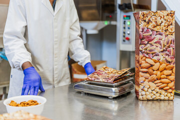 Close up of a scale weighing almonds with worker in the background at a food packaging facility