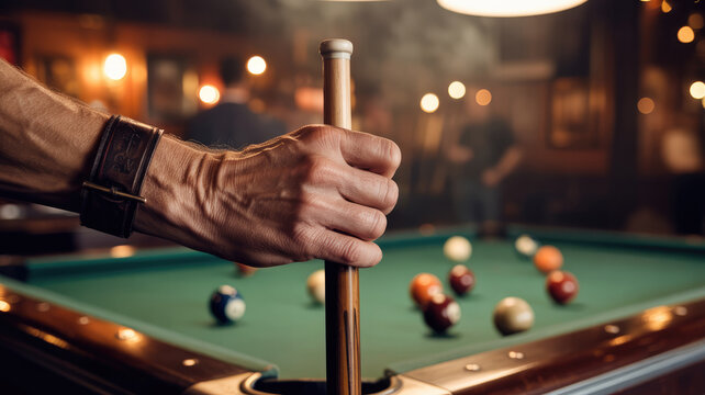 A man is playing pool with a group of balls on the table. He is holding a pool stick and is about to hit one of the balls