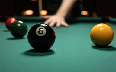 A man is playing pool and has just hit the 8 ball. The pool table is green and the balls are scattered around it