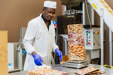 Warehouse worker weighing almonds during packaging process in a relaxed and proactive manner