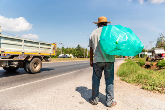 Elderly Thai man collecting recyclables walking along a highway in Tha