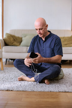 Man sitting cross-legged on floor, untangling earphones