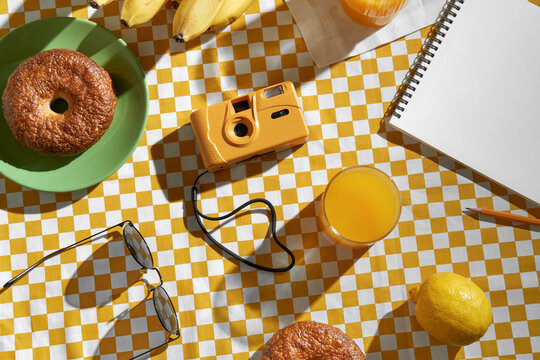 Orange film camera on yellow and white checkered tablecloth.